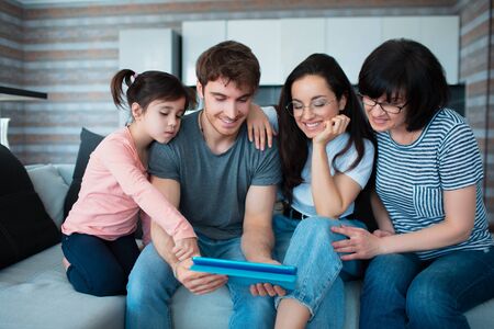 Big family at home. All together communicate online conferences on the tablet. Or play a fun mobile gameの写真素材