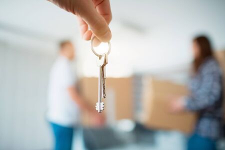 The keys in the hands of the apartment close-up. Against the background of a young seven moves to a new houseの写真素材