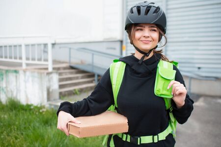Food delivery concept. The Pizza delivery woman has a green fridge backpack. She wants to deliver...