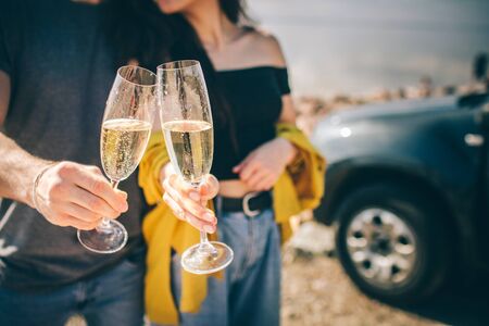 Travel, tourism - Man and woman drink champagne near the water at a folding portable table. Picnic...