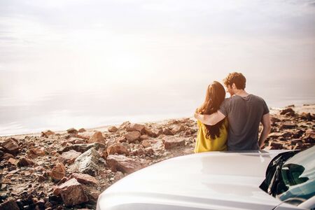 Car Travel, tourism - Happy Couple Driving on Country Road into the Sunset in Sports Carの写真素材