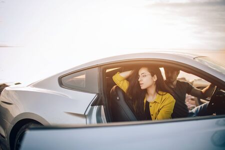Trendy young women and man traveling by car. Relaxed happy couple on summer roadtrip travel vacation
