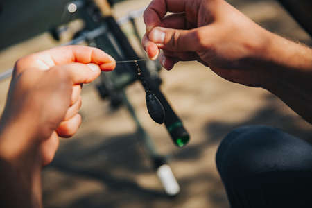 Young fisherman fishing on lake or river. Close up and cut view of guy holding fishing rod and reel...