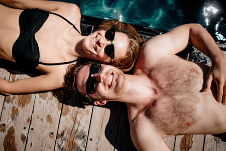 Picture of cheerful man and woman lying close to each other and enjoying company. Looking up and smile.の写真素材