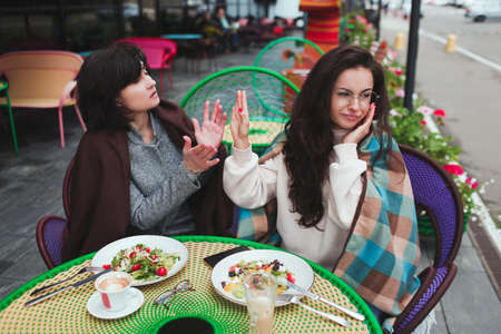 Mature mother and her young daughter sit together in cafe or restaurant. Misunderstanding in family....