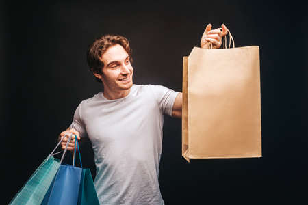 Young european man choosing gift in shopping bags