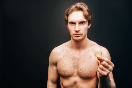 Serious european man showing condom in handの写真素材