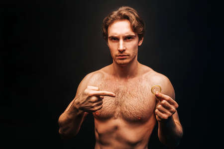 Serious caucasian man show condom in handの写真素材