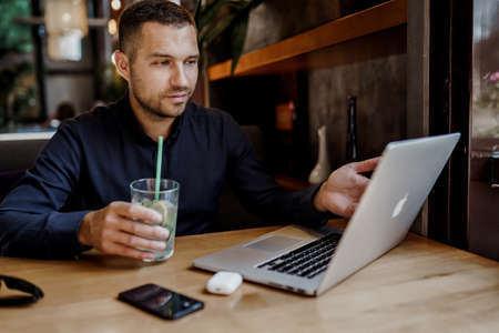 Young businessman is having online meeting on laptop in restaurant. Remote work.の写真素材