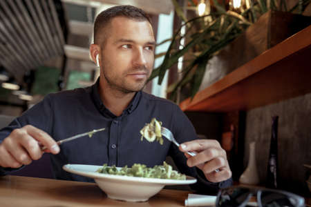 businessman in EarPods is having lunch in restaurant. listening to music.の写真素材