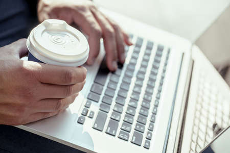 Close up young businessman holding his laptop and coffee