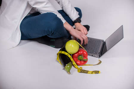 healthy eating and diet concept - natural food on table .Healthy food, diet, vegetables. A man sits in front of a computer, makes a plan for a healthy diet.の写真素材