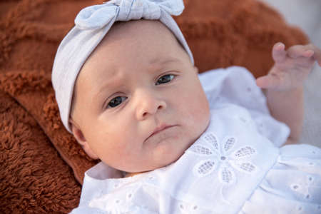 a newborn child lies on a blanket, on the shore. flowers lie nearby.