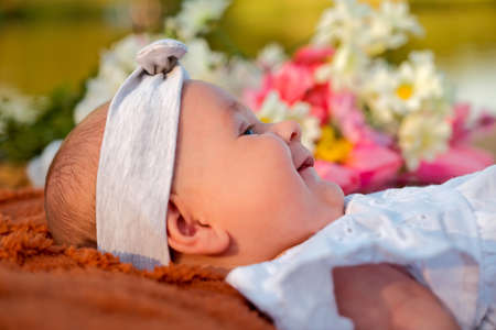 newborn baby girl lies on the beach. in a white dress.