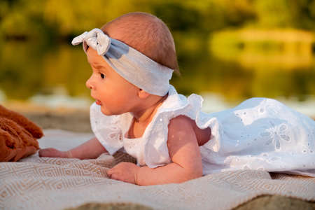 newborn baby girl lies on the beach. in a white dress.の写真素材
