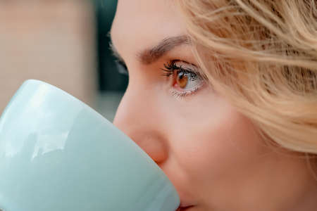 girl drinking coffee on the street. a cup of coffee. a cup of coffee and a girl's face close-up.の写真素材