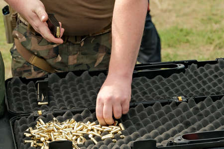 a man loads cartridges into a clip. live ammunition and pistol