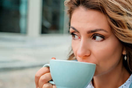 girl drinking coffee on the street. a cup of coffee. a cup of coffee and a girl's face close-up.の写真素材