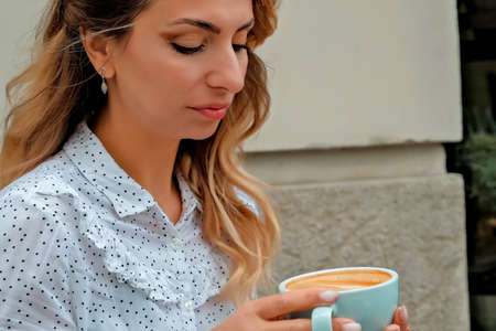 girl drinking coffee on the street. street cafe. beautiful girl and coffee.