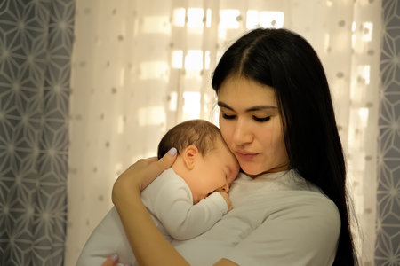 mother holds a child, a baby in her arms. the child wants to sleep.の写真素材