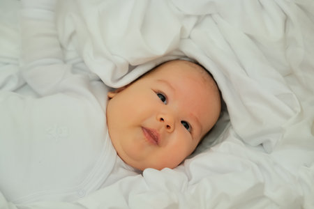 newborn baby smiles and laughs. shows emotions. baby lies on a white cloth