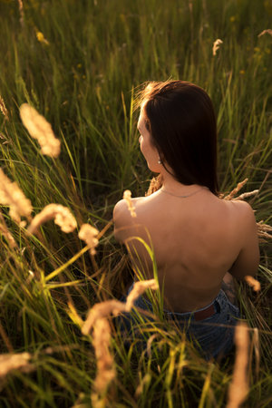 Beautiful young woman in the wheat field at sunset. back view.の写真素材