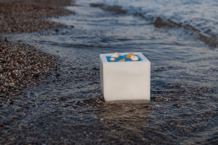 Photo of a candle in the water on the beach.の写真素材