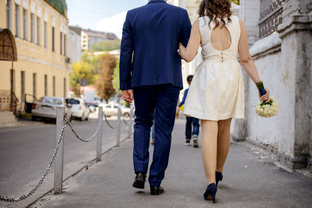 A wedding couple walks down the street holding hands.の写真素材