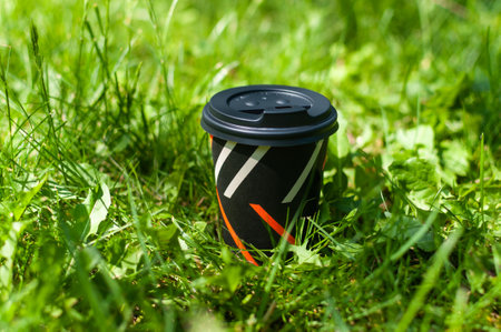 Takeaway coffee cup on green grass.