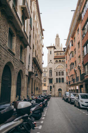 A narrow city street with cars parked on the side of a buildingの写真素材