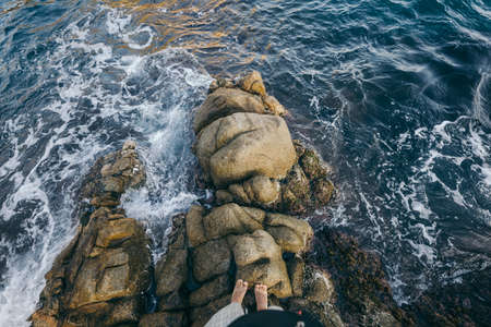 A person sitting on a rock next to waterの写真素材