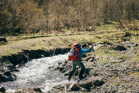 Mountains, river, man with a backpack crosses the riverの写真素材