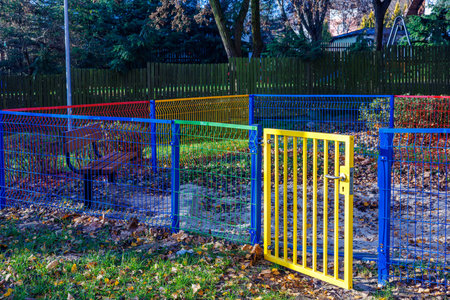 An empty children's sandbox fenced with a bright, colored fence. Open gate. High quality photo