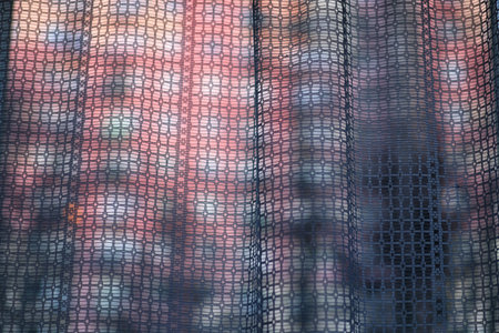 Abstract light streaming through a curtain in a dark room with a building blurred in the backgroundの写真素材