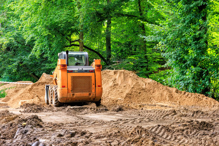 An orange mini-loader removes soil from the park.の写真素材