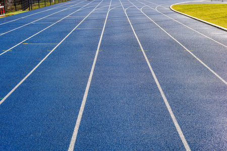 Blue running track at the new stadium, next to the artificial green turf. White lines of the running tracks. High quality photoの写真素材