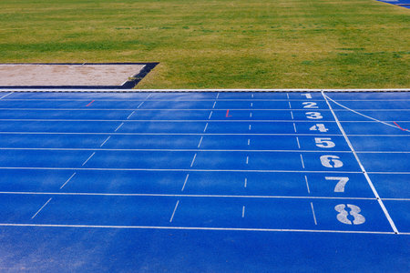 Blue running tracks with white numbers. Sand pit for long jumps.