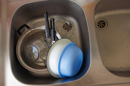 Ceramic and plastic dishes in the sink, ready to be dried with a towel. Hand washing dish concept.の写真素材