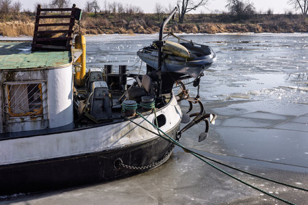 The stern of a river barge with rigging and ropes thrown over the pier. A barge on an ice-bound river. High quality photoの写真素材