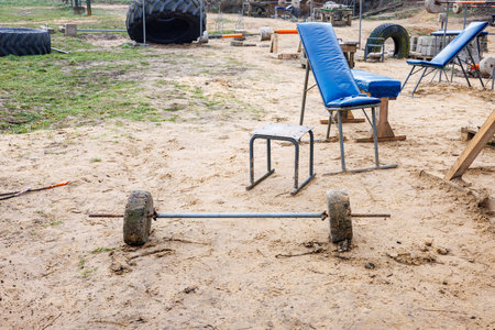A barbell made of concrete and reinforcement on the sand of an improvised sports ground on the street.の写真素材