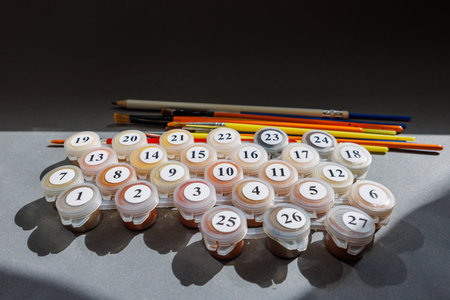 Numbered paint cans and brushes on a gray background. Painting by numbers. Painting set. High quality photoの写真素材