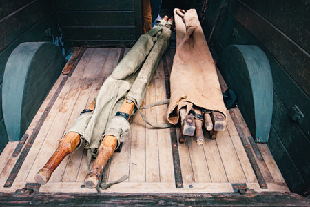 Two old canvas stretchers with wooden handles lie in the back of a car. Stretcher for carrying the wounded from World War II. High quality photoの写真素材