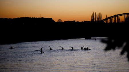 A group of kayakers in kayaks on a river in the rays of the setting sun. Active water sport and recreation. View from above.の写真素材
