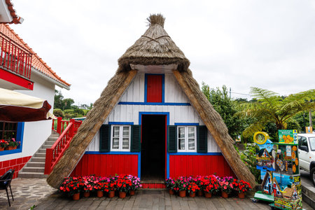 Santana, Madeira, Portugal - July 11, 2025; A traditional, brightly painted, pyramid-shaped house with doors open to the public. High quality photo