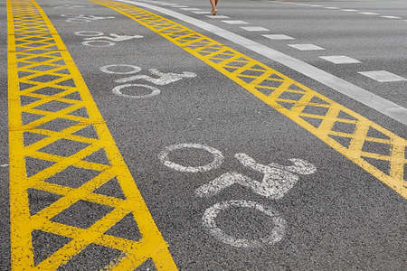 a yellow bike path crosses the road. man goesの写真素材