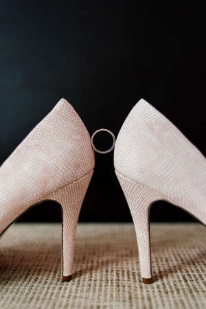 Wedding ring is between the bride's shoe on a dark background.の写真素材