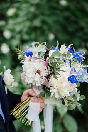 The groom holding a wedding bouquet of peonies on which stag beetle sittingの写真素材