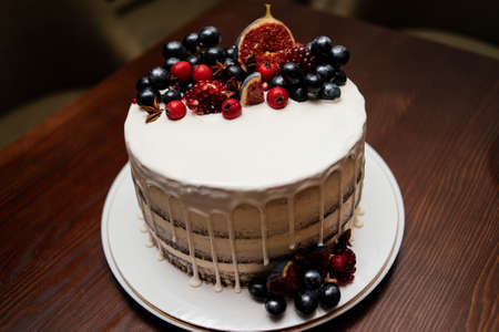 Birthday cake decorated with fresh fruit on a white plate on a wooden table. A wedding cake.の写真素材