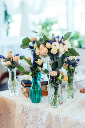 Dream and blue flowers in vases on a table with a lace tablecloth. Wedding decorations.の写真素材
