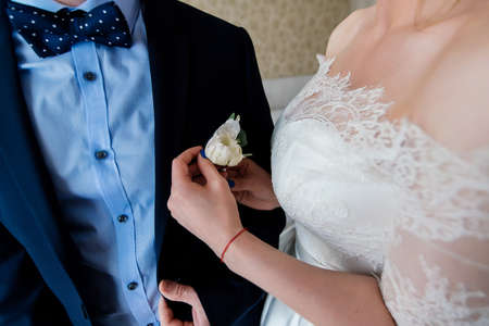 Bride fastens groom boutonniere to buttonholeの写真素材